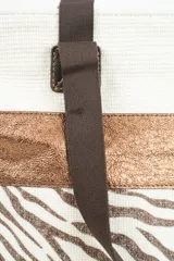 Bolso tipo tote bag de tela color beige con estampado de estrellas negras en la parte inferior y una franja horizontal negra brillante en el medio. Tiene asas de tela color beige claro y detalles de cuero sintético negro en los puntos de unión de las asas.