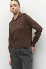 Sweater de punto beige con cuello tipo polo y diseño trenzado, de manga larga y textura suave.