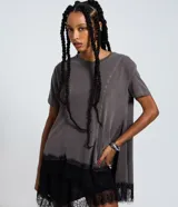 Remera de algodón color gris desteñido, con recortes asimétricos, mangas cortas y bajo irregular con encaje negro.