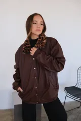 Campera negra de eco cuero con cuello de piel sintética con estampado de leopardo y cierre con botones a presión.
