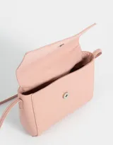 Bandolera color beige de cuerina con solapa, tag metálico y correa larga regulable.