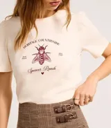 Blusa slim de algodón color crema, con cuello redondo y mangas cortas abullonadas. Presenta un estampado con lettering en inglés y una ilustración de una abeja.