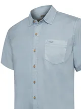 Camisa de manga corta color celeste, marca RKF, confeccionada en tencel. Tiene cuello clásico, cierre con botones claros, un bolsillo en el pecho y pinzas en la espalda.