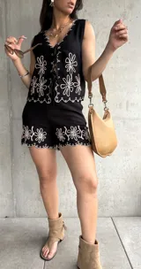 Conjunto negro de lino con bordados florales blancos. Incluye chaleco con lazo frontal y short con ruedo festoneado.