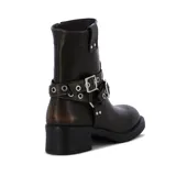 Botas de caña baja color marrón oscuro, con puntera redondeada y taco cuadrado. Presentan dos correas con hebillas metálicas plateadas alrededor del tobillo y ojales metálicos.