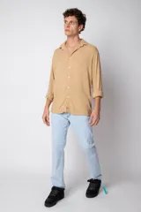 Camisa de manga larga color beige de lino, con cuello clásico y cierre frontal con botones.