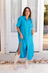 Vestido camisero de muselina color negro, de largo midi, con cuello clásico, manga corta y cierre frontal con botones.