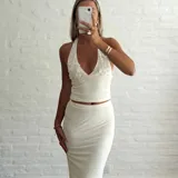 Conjunto color beige compuesto por un top halter con apliques circulares y una falda midi ajustada.