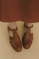 Sandalia marrón de cuero vacuno con diseño de tiras entrecruzadas, hebilla lateral y taco bajo de 2,5 cm.