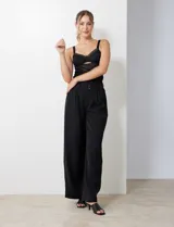 Pantalón negro de tiro alto, corte ancho y pierna fluida, con detalle de doble botón y cierre frontal.