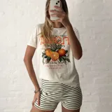 Remera blanca de algodón con estampado de naranjas y texto en color naranja.