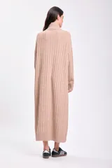 Vestido largo de punto canalé color beige, con cuello alto y diseño de mangas largas.