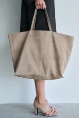 Bolso tipo maxi shopper color beige de ante, con doble asa de hombro y bolsillo interior con cremallera.