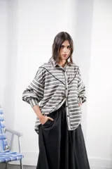 Camisa color crudo a rayas, de corte oversized con hombros caídos y silueta amplia. Presenta un recorte delantero con vivo contrastante, botones al frente y logo bordado al frente.