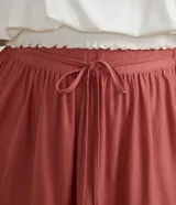 Falda larga color ladrillo con cintura elastizada y cordón ajustable. Presenta volados en el ruedo.