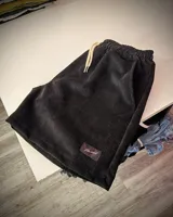 Short negro de pana con cordón ajustable en la cintura y logo bordado en la pierna.