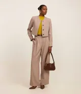 Pantalón de vestir color beige con cintura sencilla, pliegues delanteros y corte palazzo.