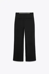 Pantalón negro de tiro medio con cinturón a tono con hebilla metálica, bolsillos delanteros y falsos bolsillos traseros.