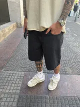 Bermuda de jean negra gastada, corte amplio a la rodilla.