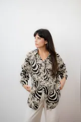 Camisa de mujer con estampado animal print en tonos beige y negro, de mangas largas con puños ajustados y corte moderno.