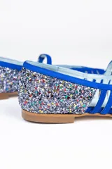 Bailarinas de piel violeta con glitter multicolor en punta y talón, diseño calado y pulsera con hebilla. Incluyen plantilla de piel y plantilla extra de lana intercambiable. Fabricadas en España.