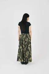 Falda maxi con estampado de camuflaje, cintura elástica y doble hebilla ajustable de herrajes metálicos. Con pliegues relajados y silueta amplia.
