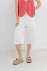 Bermuda de tiro medio color crema, con corte recto y largo a la rodilla. Diseño amplio tipo culotte corto, con dobladillo ancho en el ruedo. Presenta bolsillos delanteros y traseros funcionales.