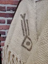 Ruana color crema tejida en lana merino con bordados a mano sobre lino.