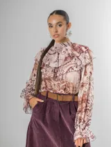 Camisa de seda italiana con estampado sutil de animal print en tonos marrones y rosados. Presenta cuello alto con volados y mangas largas con puños fruncidos.