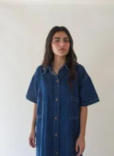 Vestido camisero corto de denim azul, con cuello camisero, mangas cortas y abotonadura frontal.