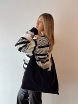 Bolso tipo hobo de gamuza sintética color negro con cierre dorado y compartimentos internos.
