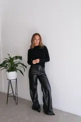 Pantalón negro de cuero sintético, corte palazzo y tiro alto.