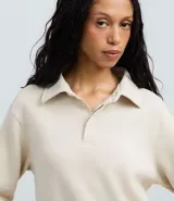 Saco femenino cerrado de algodón con felpa más sostenible, color beige. Presenta cuello polo con abotonado parcial, manga larga y bajo ajustado.