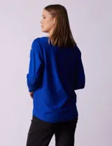 Buzo azul tejido en hilado fino, marca Cable & Gauge. Escote redondo con calados. Manga ¾, modelo dolman. Mangas con aplique de botones.