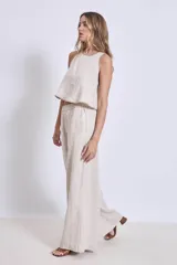 Conjunto de lino color beige, compuesto por un top sin mangas con cuello halter y un pantalón palazzo de tiro alto con cintura elastizada.