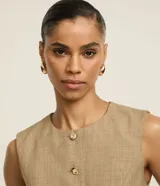 Short pollera de poliéster color beige, de corte sastrero, con cintura alta, pliegues delanteros y cintura lisa.