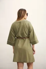 Vestido corto color beige con cuello en V y mangas tres cuartos. Presenta costuras decorativas en color marrón en cuello, mangas y frente.