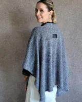 Ruana tejida en lana color gris claro, de corte amplio y diseño abierto.