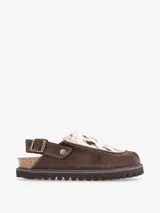 Zueco de cuero marrón con estampado animal de vaca, plantilla anatómica y hebilla ajustable al tobillo.