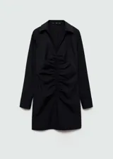 Vestido corto camisero negro con finas rayas verticales blancas, cuello camisero, mangas largas con puños abotonados, cierre frontal con cremallera y frunces verticales en el centro.