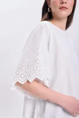 Remera blanca de algodón con mangas cortas y detalle de broderie calada en los bordes.