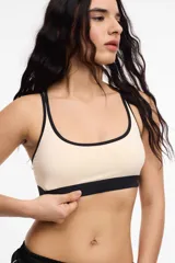 Top deportivo color beige con contorno y tirantes negros, con copas removibles y breteles finos.