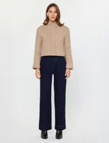 Campera corta de mujer color beige, con textura capitoneada irregular y cuello alto abotonado. Presenta cierre frontal oculto y bolsillos laterales.