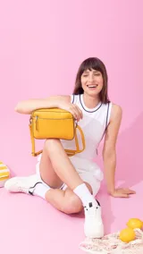 Bandolera color beige con diseño geométrico en el frente, cierre superior y correa larga regulable.