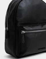 Mochila negra de cuerina con correas regulables, manija superior, cierre superior con doble deslizador, bolsillo frontal con cierre y deslizador, etiqueta metálica y bolsillos laterales.