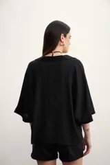 Blusa negra de lino con cuello polo y mangas cortas amplias.