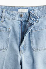 Pantalón de jean celeste de pierna ancha, tiro alto, con bolsillos de parche delanteros y traseros.