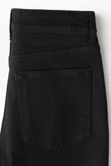 Pantalón de jean negro de corte skinny, tiro alto y cinco bolsillos.
