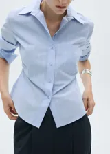 Camisa celeste a rayas verticales, de corte entallado, con cuello camisero, cierre de botones y mangas largas.