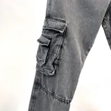 Pantalón jean gris oscuro con efecto lavado, corte holgado, bolsillos laterales tipo cargo con fuelle y doble bolsillo con solapa.